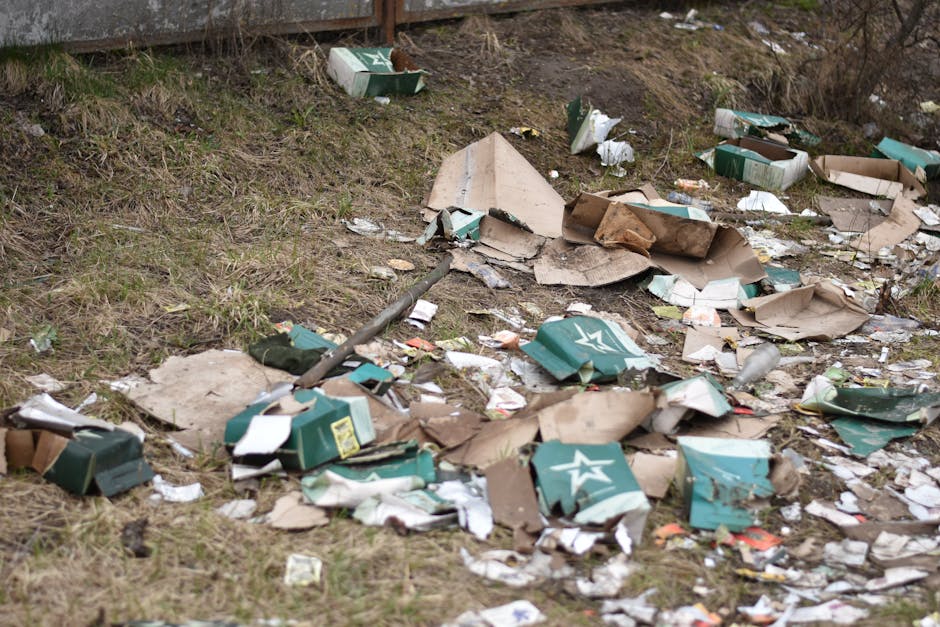 A collection of mixed rubbish and waste items is piled up on a paved area in front of a commercial building. The waste includes various brown, white, and black plastic bags, some tightly sealed and ot